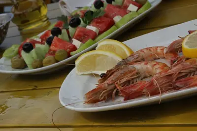 two plates of food with shrimp and fruit on a table at FKK Ada Bojana in Ulcinj