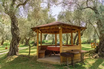 a wooden gazebo in a park with trees at Apartments Aura in Utjeha