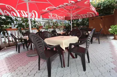a group of tables and chairs with red umbrellas at Apartments Memidz in Budva