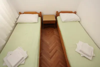 two beds in a small room with a table at Apartments Memidz in Budva