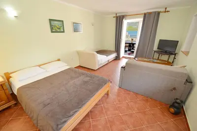 a bedroom with a bed and a couch and a television at Dubravcevic Residence in Tivat