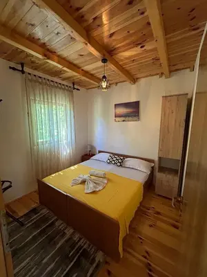 a bedroom with a large bed in a room with wooden ceilings at Cottage Ajna - Ada Bojana in Ulcinj