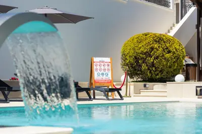 a fountain in a pool with a table and an umbrella at Guest House Pasha in Ulcinj