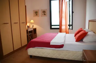 a bedroom with a bed with red pillows and a window at Apartments Secret Garden in Sveti Stefan