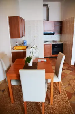a kitchen with a wooden table and white chairs at Apartments Secret Garden in Sveti Stefan