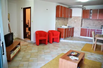 a living room with two red chairs and a kitchen at Apartments Secret Garden in Sveti Stefan