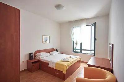 a bedroom with a bed and a chair and a window at Apartments Secret Garden in Sveti Stefan