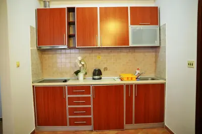 a kitchen with wooden cabinets and a sink at Apartments Secret Garden in Sveti Stefan