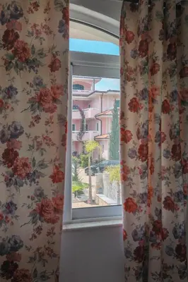 a window with floral curtains and a view of a building at Casa Selimi in Ulcinj