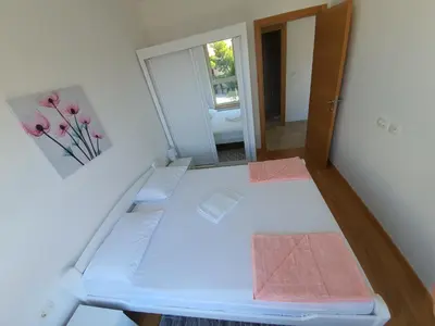 a room with a white bed with a mirror at AS Apartments Rafailovici in Rafailovici