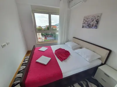a small bedroom with a bed with a red blanket at AS Apartments Rafailovici in Rafailovici