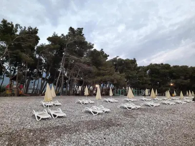 a group of lounge chairs and umbrellas on a beach at Šušanj Ilino APARTMAN in Bar