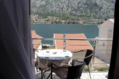 a table and chairs on a balcony with a view of the water at Apartments Marković in Kotor
