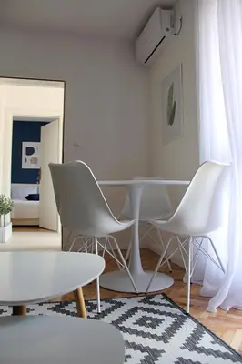 a white dining room with white chairs and a table at Apartments Marković in Kotor