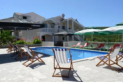 a group of chairs and umbrellas next to a swimming pool at Apartments Vila Lazarevic in Tivat