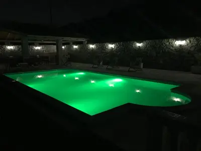 a swimming pool with green illumination at night at Apartments Vila Lazarevic in Tivat