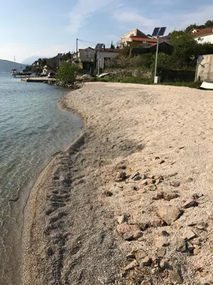 a sandy beach with houses and the water at Apartments Vila Lazarevic in Tivat