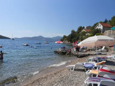 a beach with chairs and umbrellas and people in the water at Apartments Vila Lazarevic in Tivat