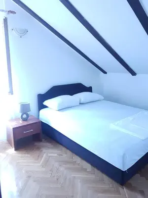 a bedroom with a white bed and a night stand at Apartmani Kovačević in Kotor
