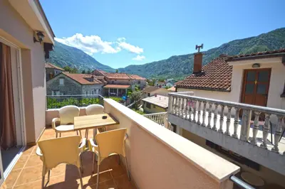 a balcony with a table and chairs and mountains at Apartmani Kovačević in Kotor