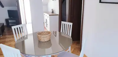 a glass table with white chairs and a basket on it at Apartmani Kovačević in Kotor