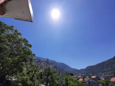 a sun in the sky over a town with mountains at Apartments Dakovic in Kotor