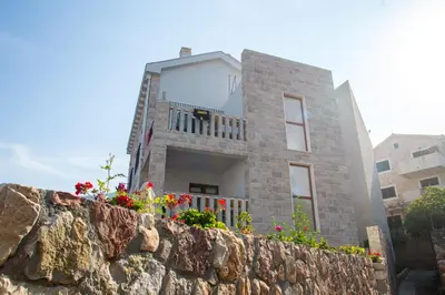 a house on top of a stone wall at Mima Apartments in Sveti Stefan