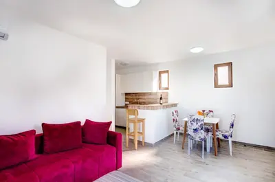 a living room with a red couch and a kitchen at Mima Apartments in Sveti Stefan