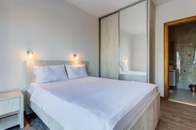 a bedroom with a large white bed and a bathroom at Mima Apartments in Sveti Stefan