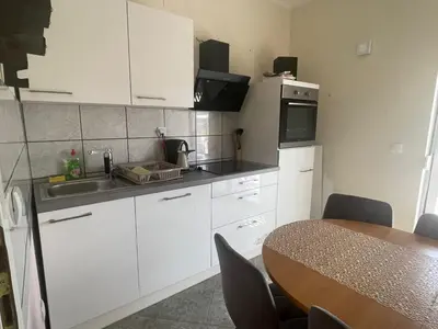 a kitchen with white cabinets and a table with chairs at Apartments Jasmina in Utjeha
