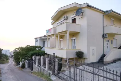 a white building with a fence in front of it at Apartments Jasmina in Utjeha
