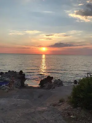 a sunset over the ocean with a person standing on the beach at Apartments Jasmina in Utjeha