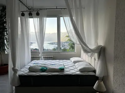 a bed in a room with a large window at Apartments Vidikovac Inn in Kotor