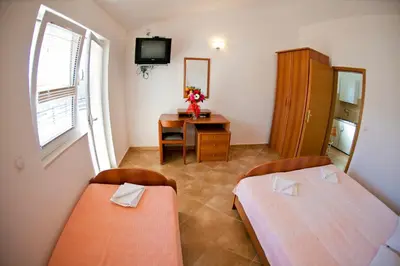 a room with two beds and a desk with a mirror at Apartments Stanka in Becici