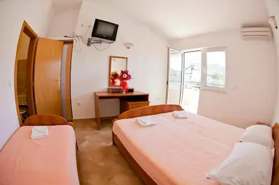 a bedroom with two beds and a tv on the wall at Apartments Stanka in Becici