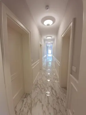 a hallway with white walls and marble floors and doors at Apartments Boreta in Budva