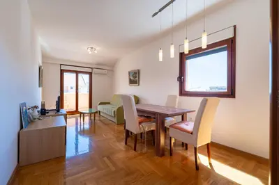 a dining room and living room with a table and chairs at Family One bedroom apartment with Panoramic city view in Budva