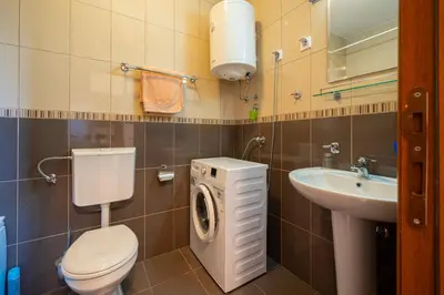 a bathroom with a toilet a sink and a washing machine at Family One bedroom apartment with Panoramic city view in Budva