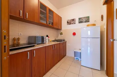 a kitchen with wooden cabinets and a white refrigerator at Family One bedroom apartment with Panoramic city view in Budva