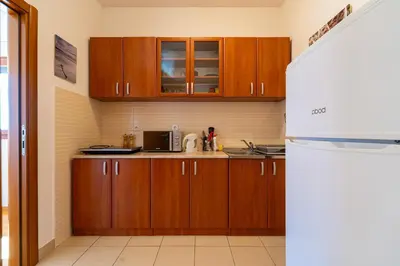 a kitchen with wooden cabinets and a white refrigerator at Family One bedroom apartment with Panoramic city view in Budva