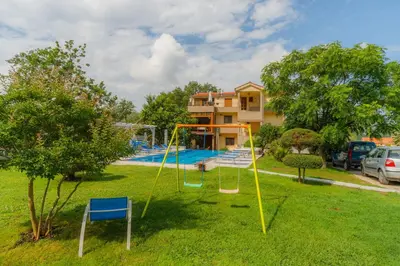 a yard with a playground in front of a house at Apartmani Novaković in Kotor