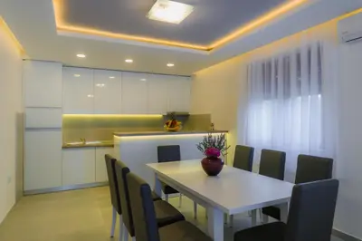 a dining room with a white table and chairs at Apartmani Novaković in Kotor