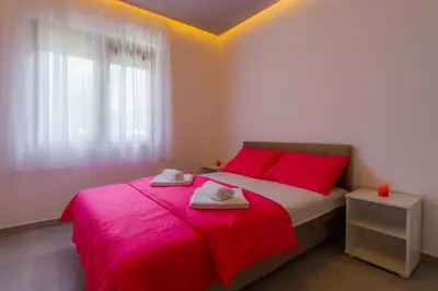 a bedroom with a red bed with towels on it at Apartmani Novaković in Kotor