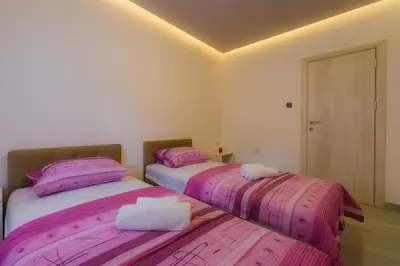 two beds in a room with pink sheets at Apartmani Novaković in Kotor