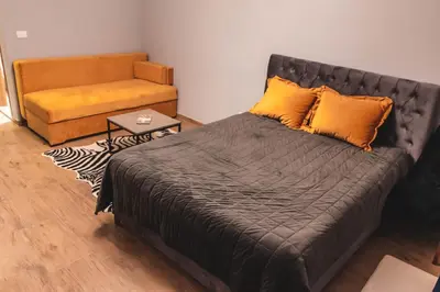 a bedroom with a bed with orange pillows and a couch at Auto kamp Titograd in Podgorica