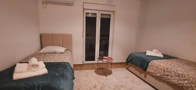 two beds in a small room with a window at Auto kamp Titograd in Podgorica