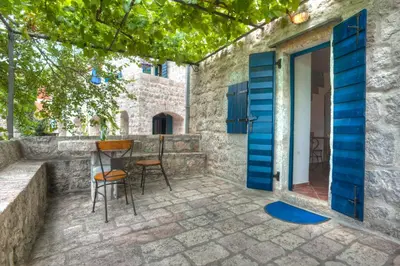 a patio with a blue door and chairs at B&B Apart Hotel Paštrovski Konak in Sveti Stefan