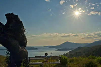 a person sitting on a bench with a view of a lake at B&B Apart Hotel Paštrovski Konak in Sveti Stefan