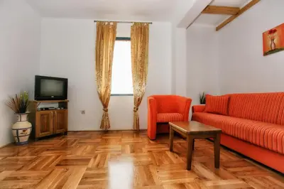 a living room with a red couch and a television at B&B Apart Hotel Paštrovski Konak in Sveti Stefan