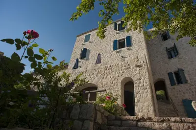 a stone building with a bunch of windows at B&B Apart Hotel Paštrovski Konak in Sveti Stefan